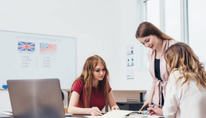 Young woman teaching English to adult students at language school